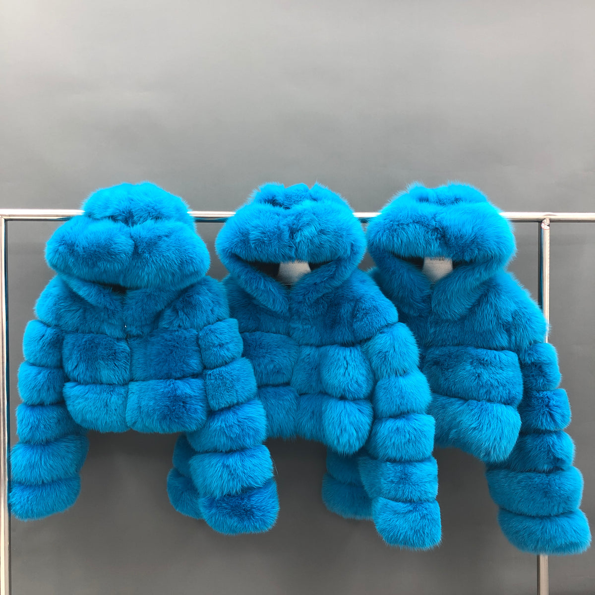 Three blue classic three-row hooded fox fur cropped jackets displayed together
